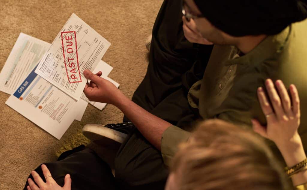 picture taken from above, couple sitting together looking at past due bills