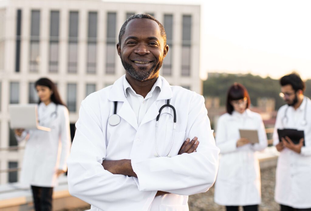 Smiling Black doctor in foreground with more doctors blurry in background